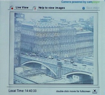 La projection seule, avant l'intervention&nbsp;: l'interface d'une webcam publique en ligne — barre de titre «&nbsp;Camera powered by camplayer&nbsp;», onglets «&nbsp;Live View&nbsp;» et «&nbsp;Help to view images&nbsp;», horloge «&nbsp;Local Time&nbsp;: 14:40:33&nbsp;» en bas. Dans la fenêtre, une vue en plongée d'un pont parisien et de ses immeubles haussmanniens, la file des voitures sur le tablier.