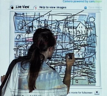 Plus tard encore&nbsp;: le tracé a envahi toute la surface. Un maillage serré de lignes noires — façades, balcons, lucarnes, arbres redoublés — sature l'image au point qu'on ne distingue plus ce qui vient de la caméra et ce qui vient du feutre. La silhouette, toujours de dos, poursuit le geste dans la partie basse du cadre.