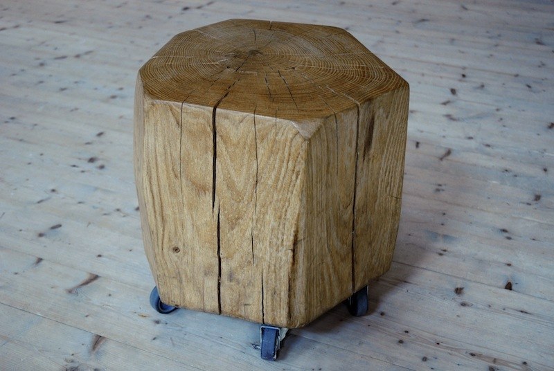 Billot&nbsp;: une bille de chêne à section octogonale, fendue par le séchage, montée sur trois roulettes, sur un plancher de pin clair.